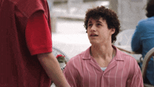 a man in a pink shirt is talking to another man