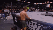a man is standing in a wrestling ring with a sign that says all elite aew