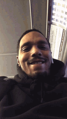 a man in a black hoodie is smiling in front of a sign that says ' columbia ' on it