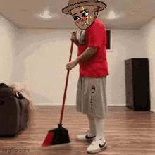 a man in a red shirt and gray shorts is sweeping the floor with a red broom .