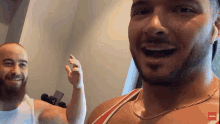 a man with a beard wearing a red and white tank top with a gold chain around his neck is smiling