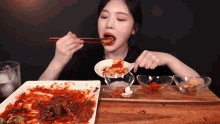 a woman is eating a plate of food with chopsticks ..