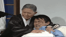 a woman is holding a man in a hospital bed while a gun is pointing at him