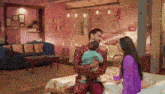 a man is holding a baby while a woman sits on a bed .