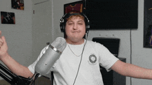 a man wearing headphones is standing in front of a microphone and giving a thumbs up