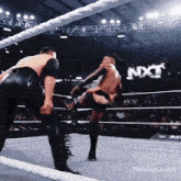 two men are wrestling in a ring with nxt written on the wall