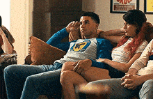 a group of people are sitting on a couch and one of them is wearing a shirt that says ' shark ' on it