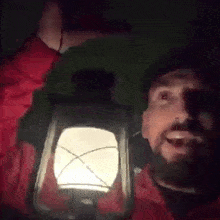 a man is holding up a lantern in the dark .