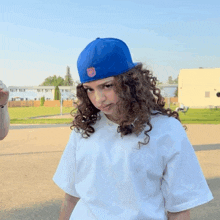 a girl with curly hair wearing a white shirt and a blue hat with the letters nhl on it