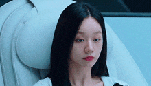 a woman with long black hair is sitting in a chair with her head resting on a white pillow .