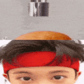 a close up of a person 's face with a red headband on their head .
