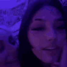 a couple of women are kissing each other in a dark room with purple lights .