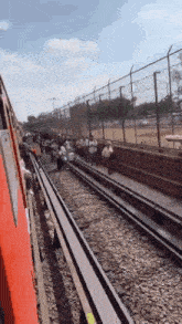 a train going down the tracks with people walking on the side