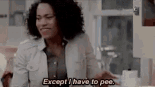 a woman is sitting at a table in a kitchen and saying `` except i have to pee . ''