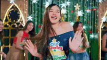 a woman is dancing in front of a christmas tree while wearing a shirt that says our stories on it .