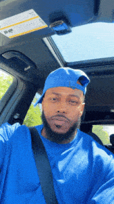a man in a blue shirt and hat is sitting in a car with a sunroof