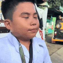 a young boy wearing a white shirt and tie with a lanyard around his neck that says ' philippines tourism ' on it