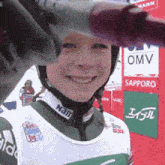a woman wearing a helmet is smiling in front of a sign that says omv on it