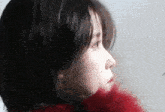a close up of a woman 's face with a red fur coat on .