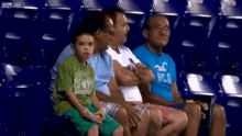 a group of people are sitting in a stadium and one of them is wearing a hollister shirt