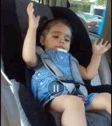a baby is sitting in a car seat with his arms in the air