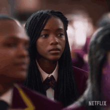 a girl with braids is sitting in a crowd of people with a netflix logo in the corner