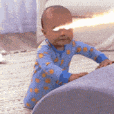 a baby wearing a blue pajama with suns on it is crawling on the floor