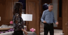 a man and a woman are standing next to each other in a living room with balloons .
