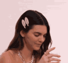 a woman wearing a necklace and a hair clip is holding a glass of wine .