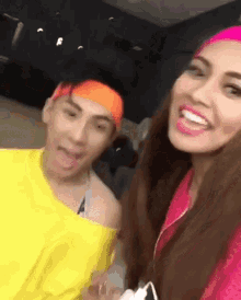 a man wearing an orange headband and a woman wearing a pink headband smile for the camera