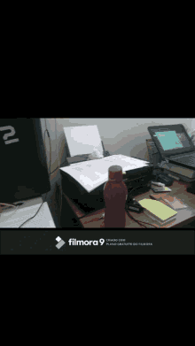 a laptop sits on a desk next to a cup and a calculator with a filmora 9 logo in the corner