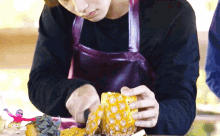 a man wearing an apron is cutting a pineapple