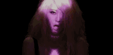 a woman with purple hair and white makeup is looking at the camera