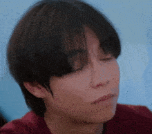 a close up of a person 's face with a red shirt on