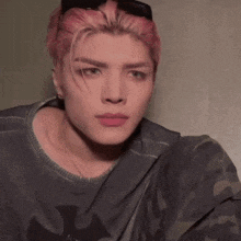 a young man with pink hair is wearing sunglasses and a gray shirt