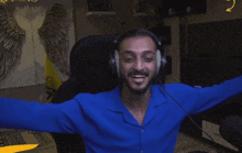 a man wearing headphones and a blue shirt is waving his hand