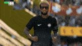 a man wearing sunglasses and a black nike shirt is running on a sports field