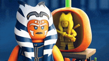 a lego figure stands next to a pumpkin with a yellow figure in it
