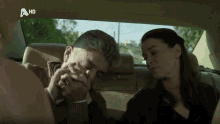 a man and a woman are sitting in the back seat of a car with a hd logo on the bottom right
