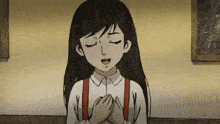 a girl in a white shirt with red suspenders is praying with her eyes closed