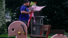 a man in a blue shirt is holding a bouquet of flowers in front of a bench that says " full " on it