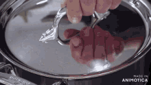 a person is holding the lid of a silver pot