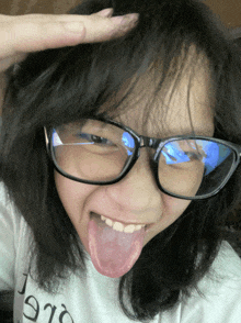 a girl wearing glasses and a t-shirt that says 1910 sticking her tongue out