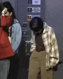 a man wearing a plaid jacket is standing in front of a door .