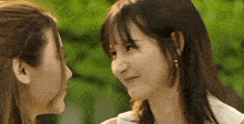 two young women are looking at each other 's faces .
