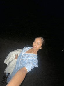 a woman in a blue dress is laying on the ground