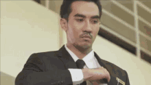 a man wearing a suit and tie is adjusting his tie .