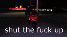a person riding a red motorcycle with the words shut the fuck up below