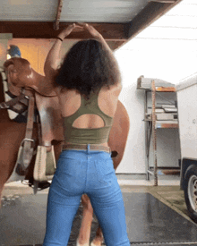 a woman in a green tank top is standing next to a horse