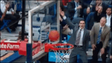 a man in a suit and tie is watching a basketball going through a hoop with a sign that says the farm